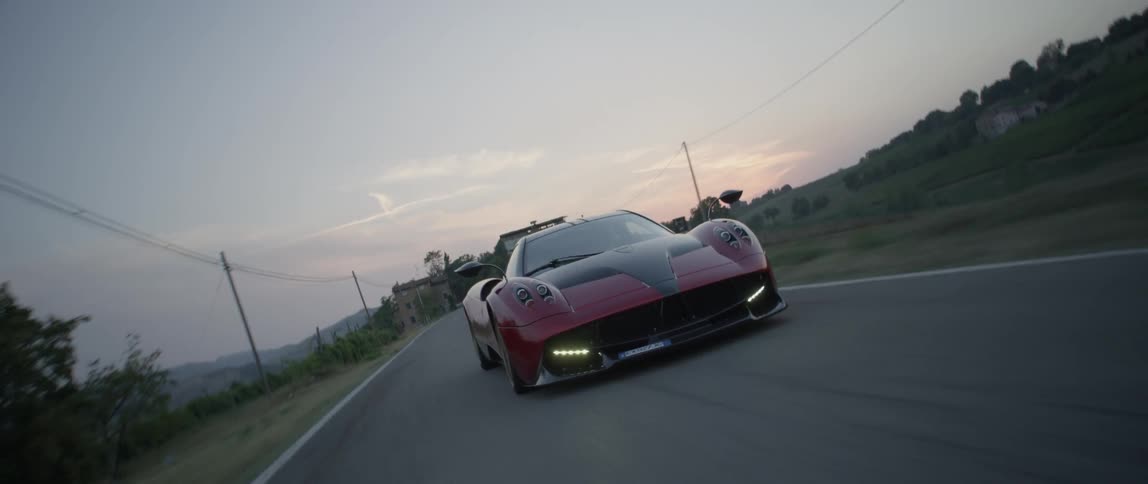Red sports car driving down a road as the camera swings from side to side
