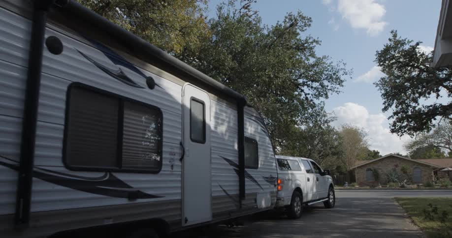 Truck pulls a large camper in a residential area
