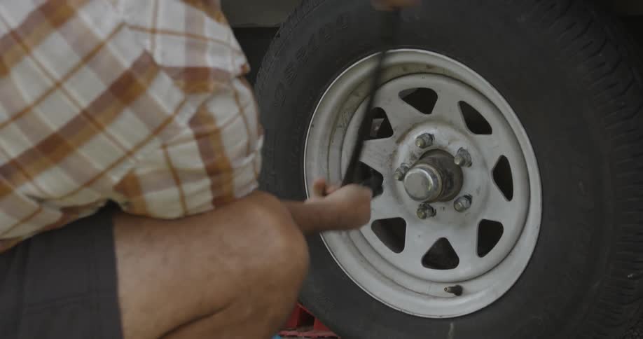 Man removing lug nuts with tire iron