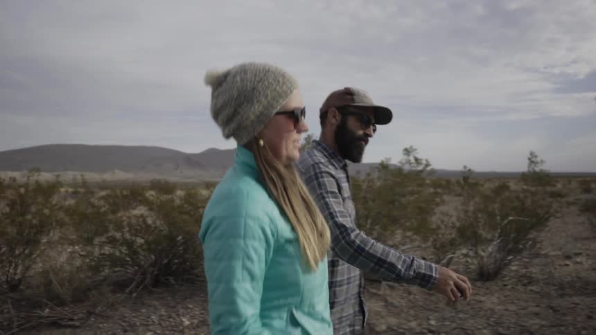A couple walk through a desert area