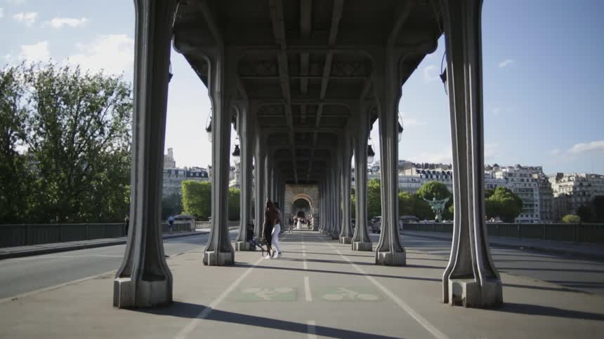 People walk on a pathway under a bridge