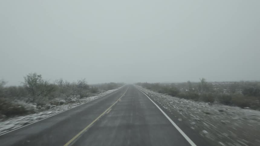 Traveling down a desolate highway during a snowstorm