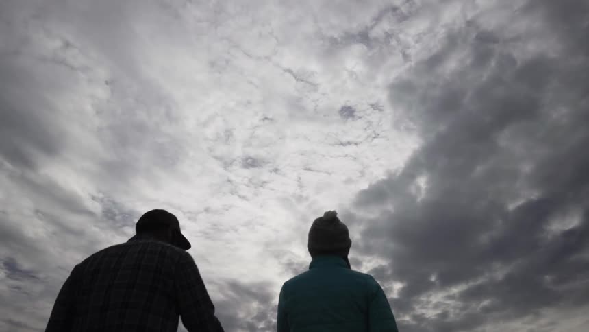 A man and woman walk outside on a cloudy day
