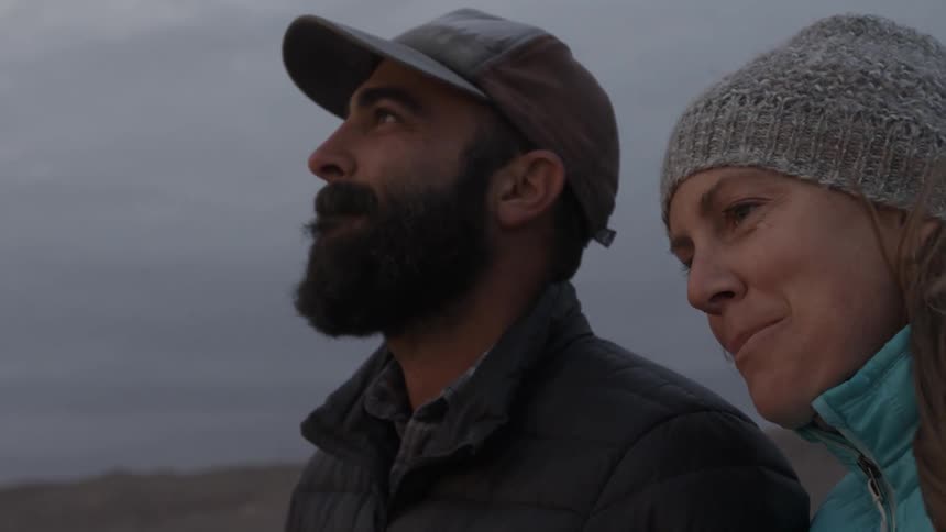 A man and woman laugh on a windy day