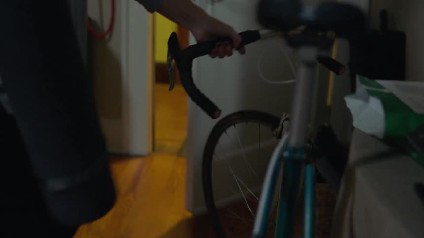 A woman wheels her bicycle out of an apartment