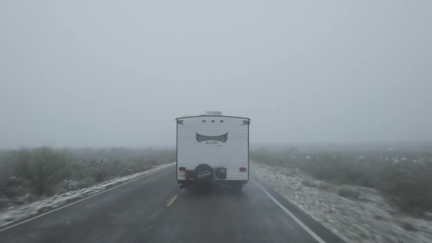 A camper is being driven on a country road in winter