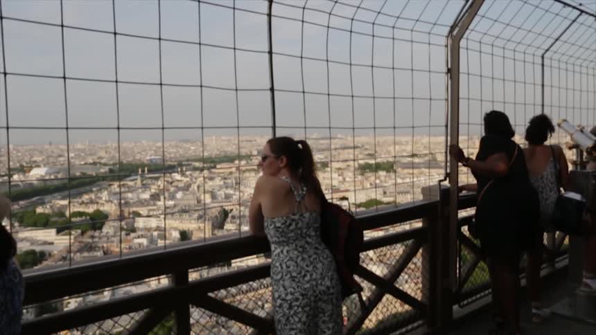 People stand at a railing looking out from an observation lookout.,