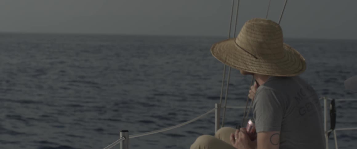 A man sits on a boat sailing on the ocean