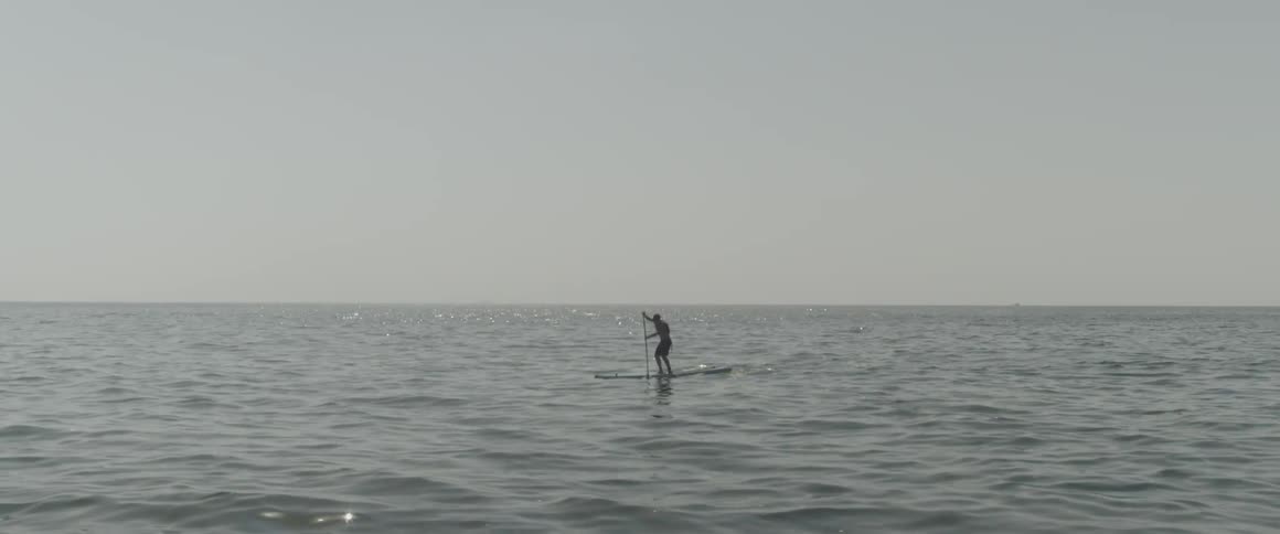 A man paddles on a board in the ocean