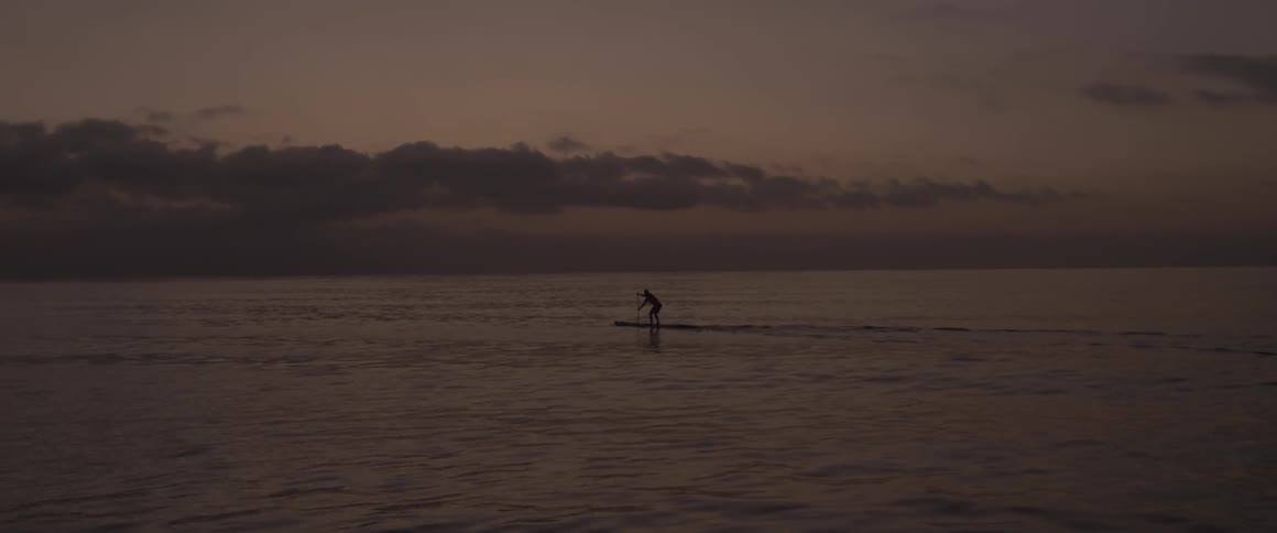 A man paddles on a board in the ocean