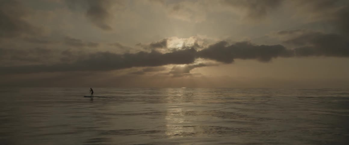 A person paddle boards in the ocean at sunset