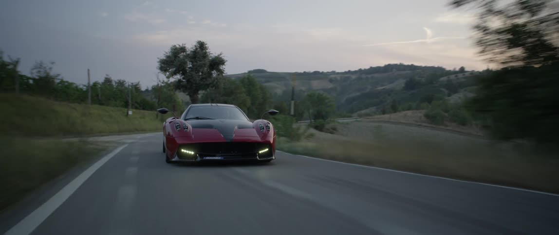 Sports car driving on country road after sunset