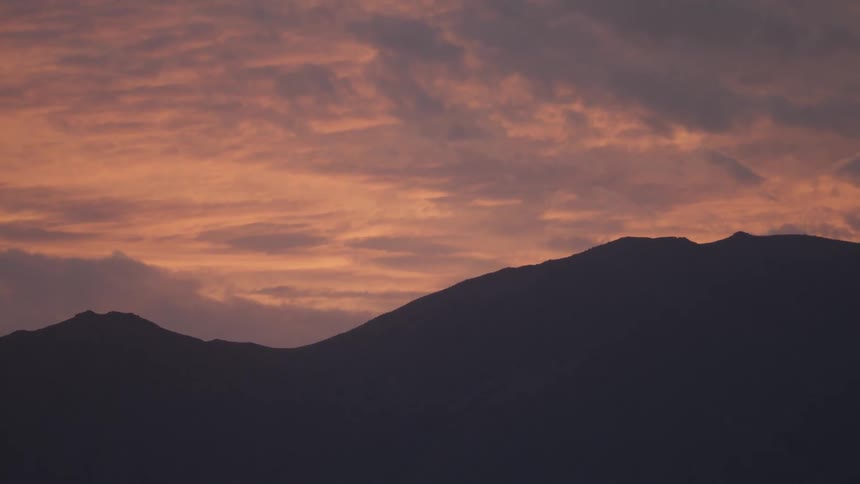 Thick clouds covering the sky over dark mountains after sunset