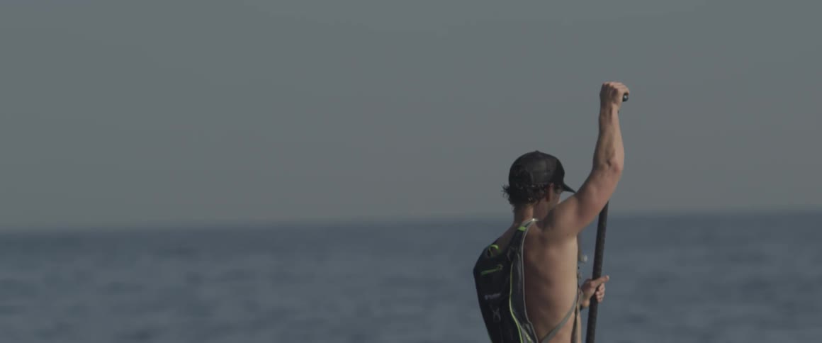 A man paddles on a board in the ocean