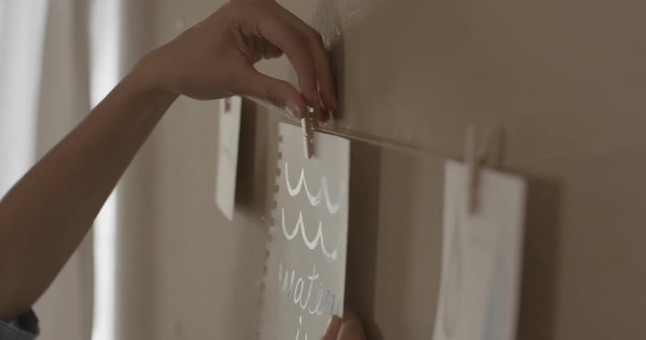 A woman hangs up a picture on clothespins