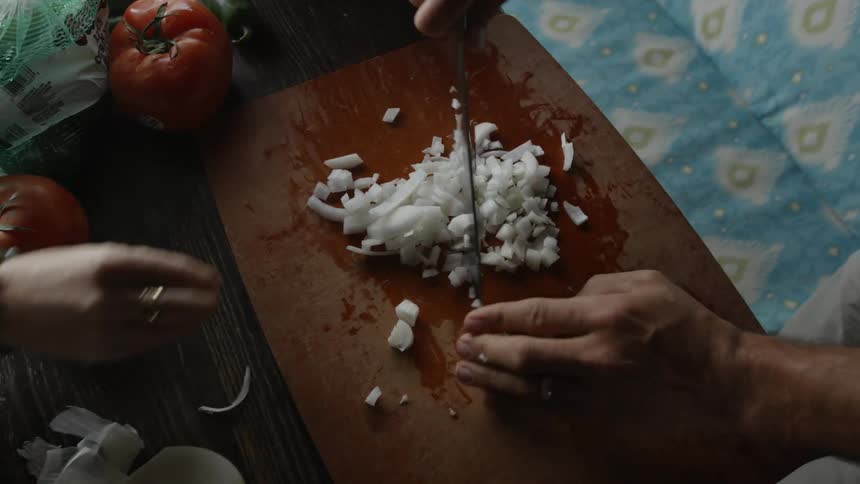 A woman dices onions on a cutting board