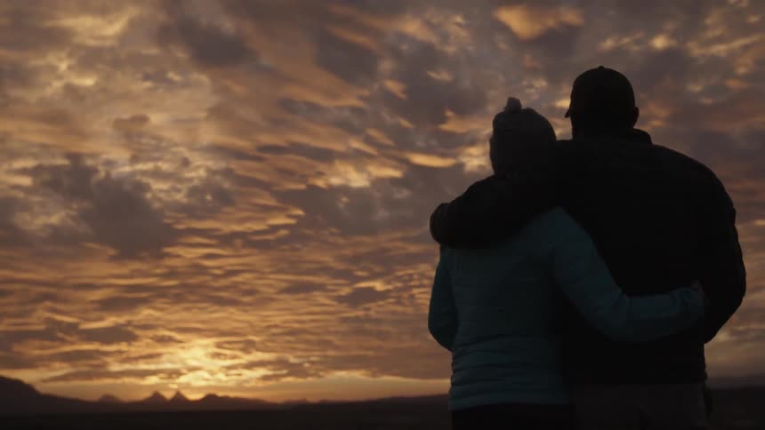 Man and woman embracing outside at sunset on cloudy evening