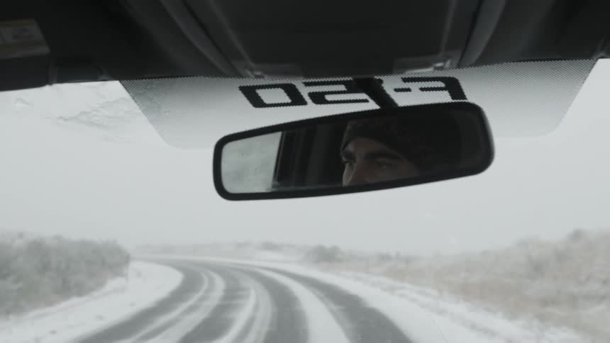 A man drives on a snowy road