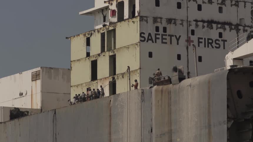 Group of men pulling a rope outside a large building