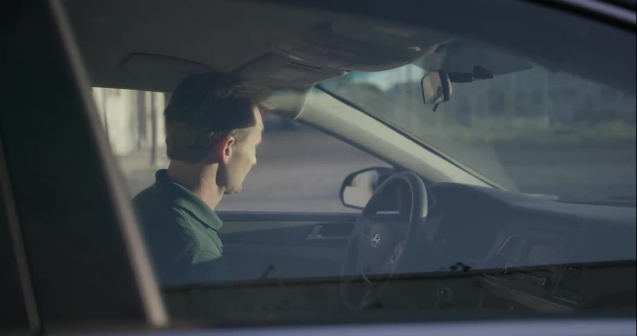 A man gets in a car and then drives away