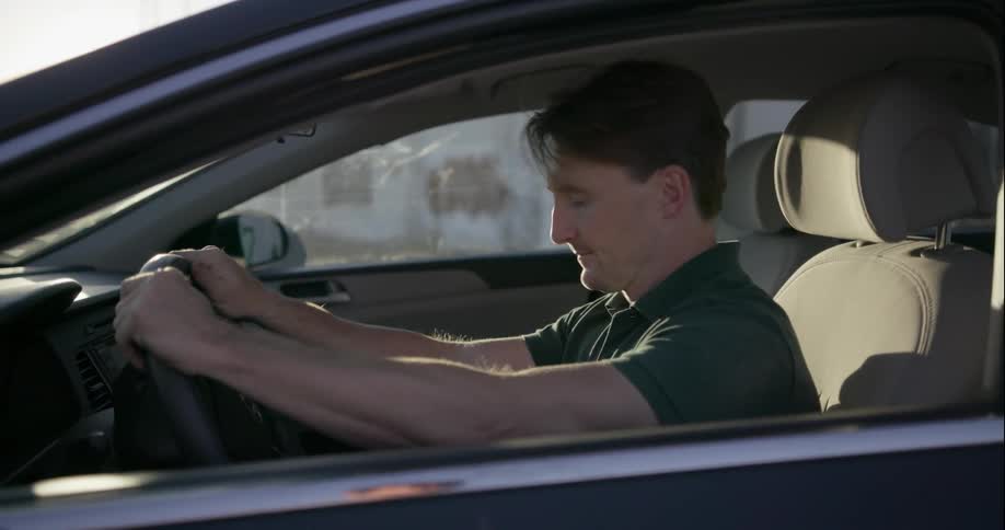 A man starts the car, but it fails and he slams the steering wheel