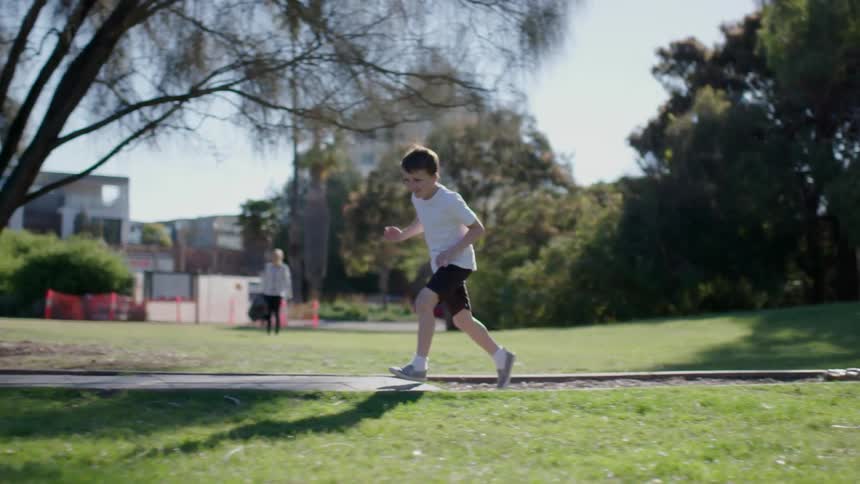 Boy running in park on sunny day