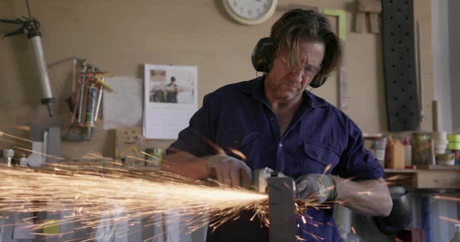Sparks fly while a man uses a power tool in a workshop