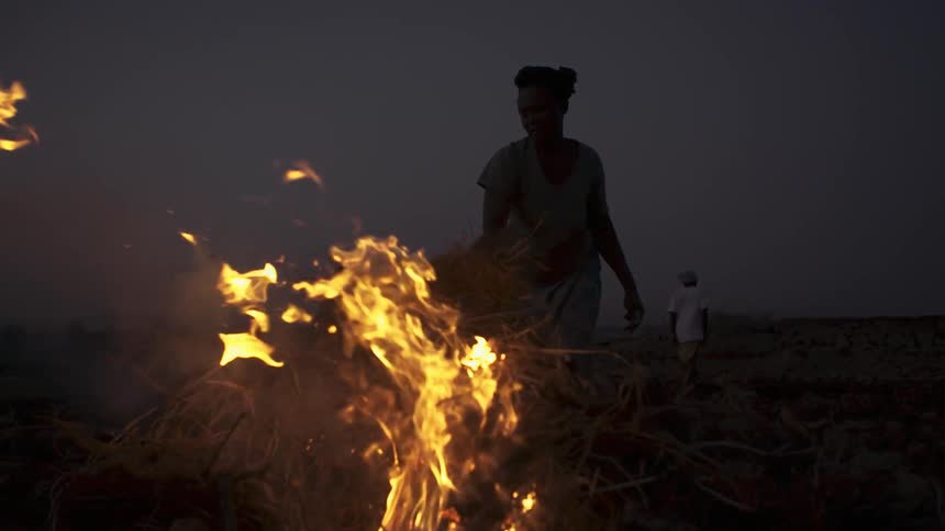 A woman throws roots on a fire