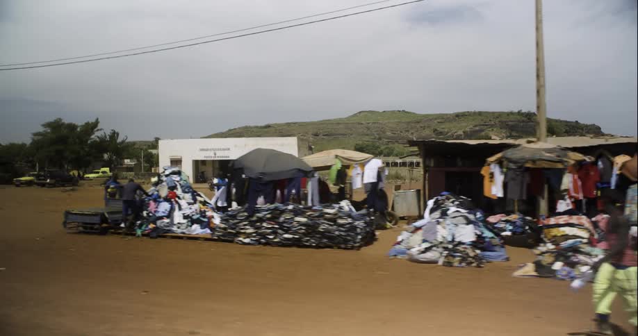 Small shops are set up along a dirt road in a small town