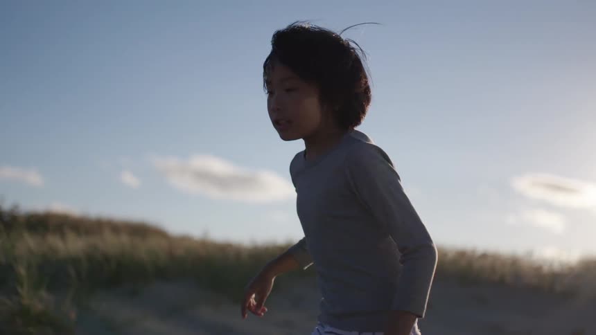A young boy runs on a sandy beach