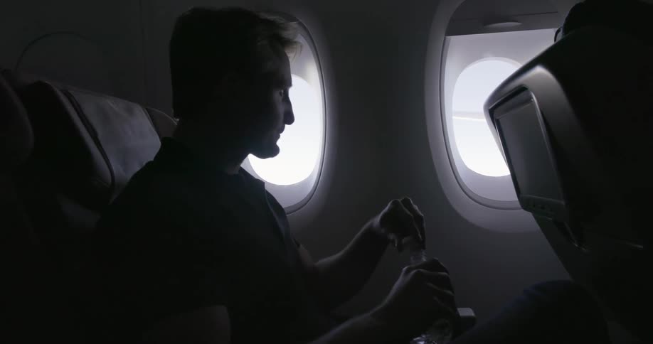 An airline passenger opens a bottle of water and takes a drink