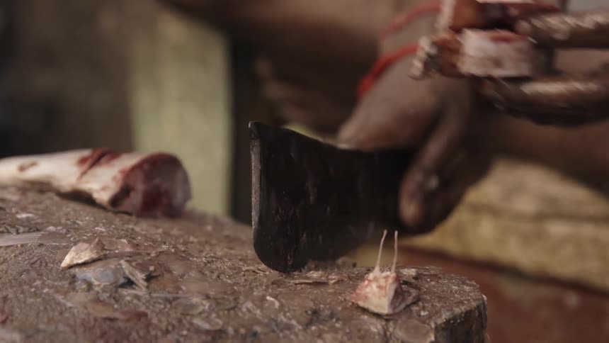 A man chops fish on a dirty block