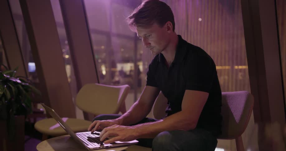 A man is sitting down typing on a laptop