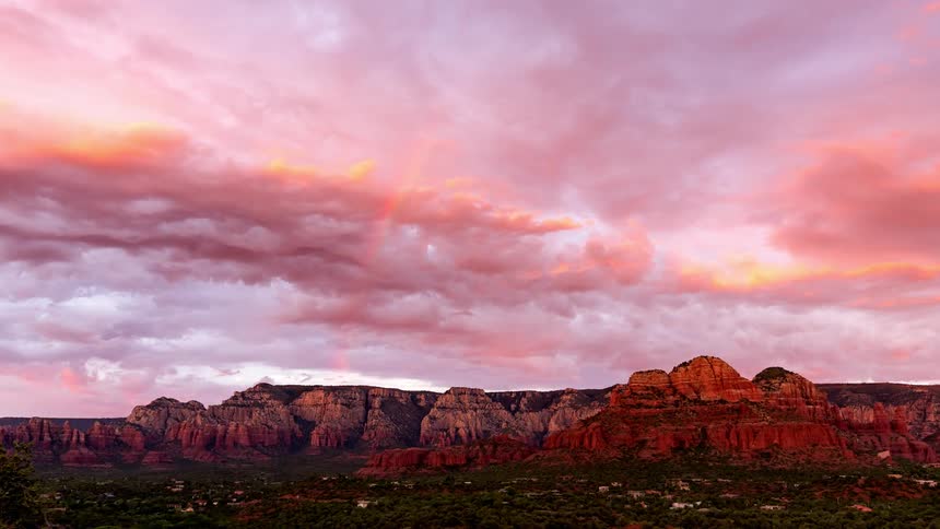 Clouds float over red rock formations at sunset