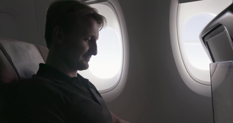 A man is taking a flight and using his laptop