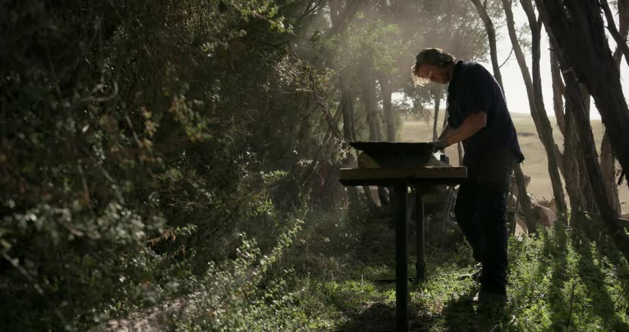 A man carves wood outdoors