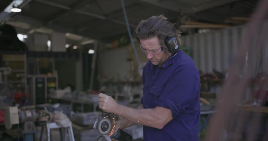 A man uses a power tool in a workshop