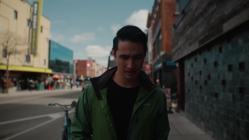 A man is walking on an urban sidewalk during the day