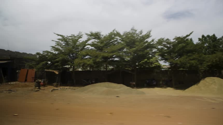 Motorcycles pass in front of piles of sand