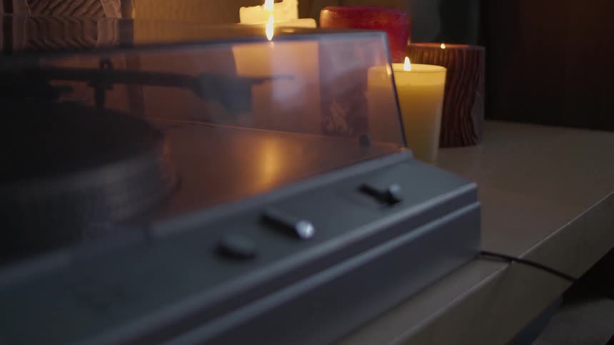 A person picks up headphones lying next to candles