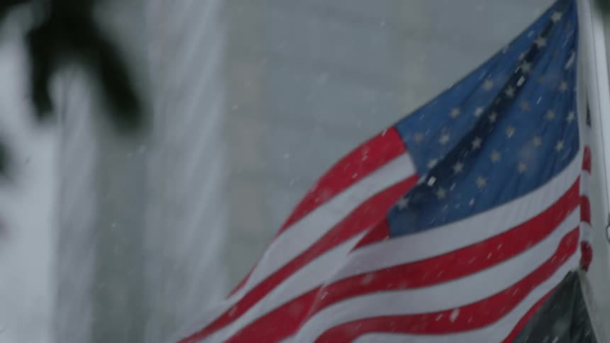 American flag waves in softly falling snow