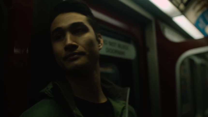A man is leaning against the doors of a moving train