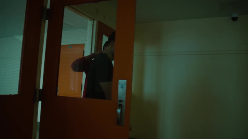 Two young men talk and interact as they walk through a hallway