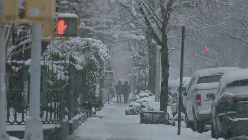 Pedestrians walk in a snowy city