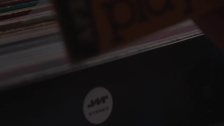 A person picks up a record album then places it back in the row