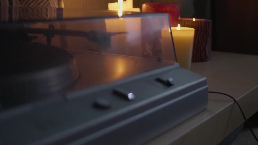 Person lifts lid of record player on a candlelit table