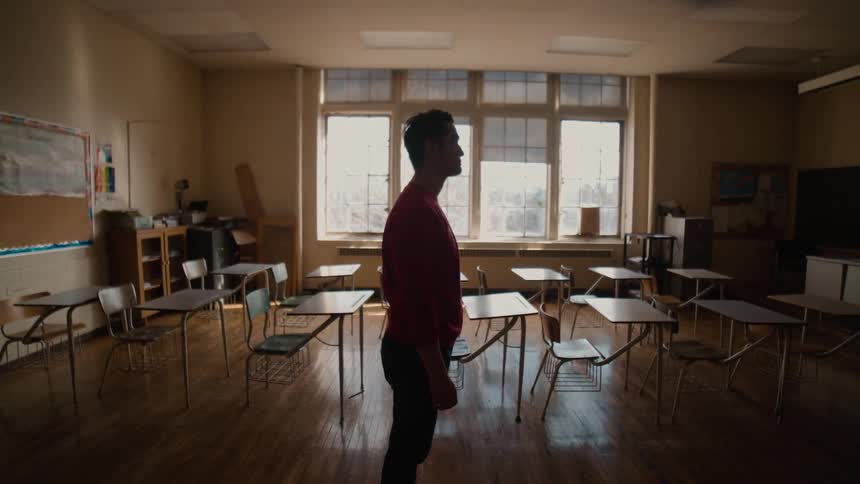 A man stands in an empty classroom