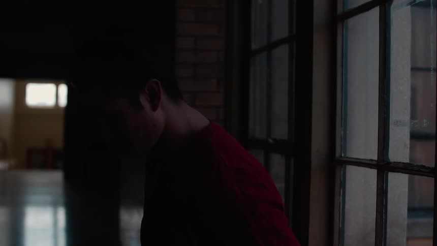 A man is standing next to a window looking at the floor