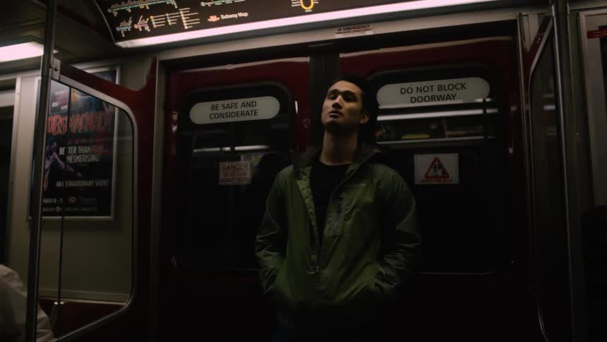 A man is traveling on a train standing up