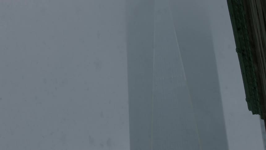 Snow falling before a skyscraper on a dark day